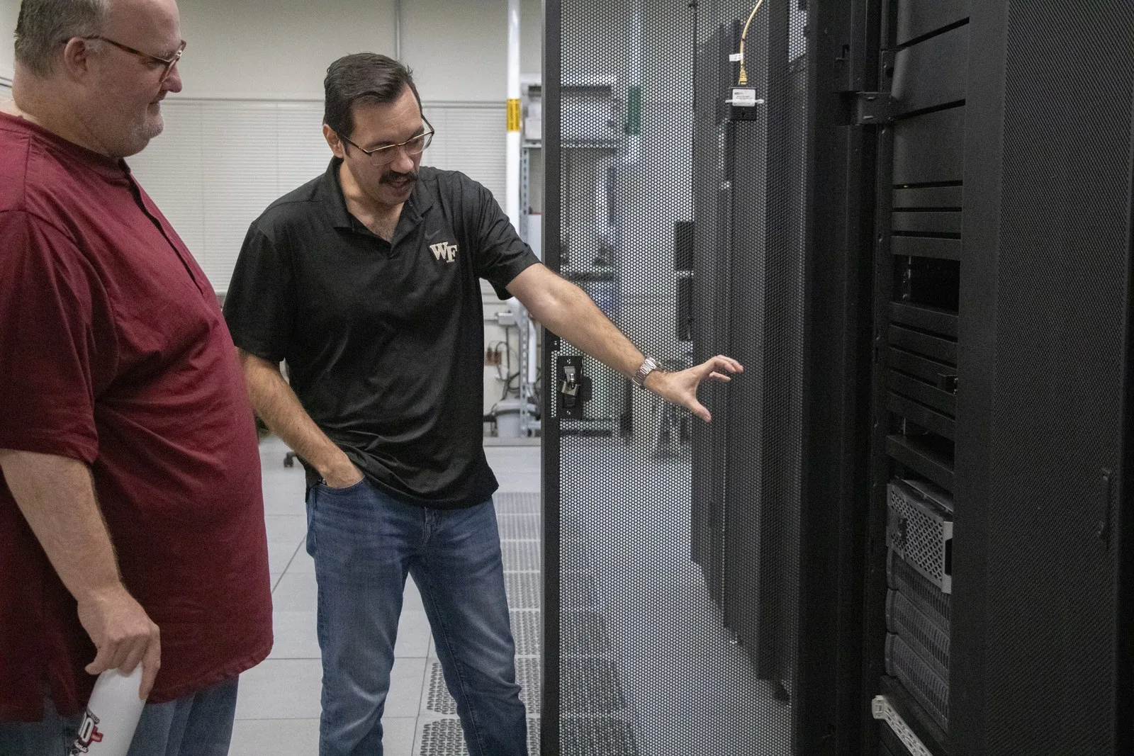 Freddie Salsbury points toward a server rack while another staff member looks on.