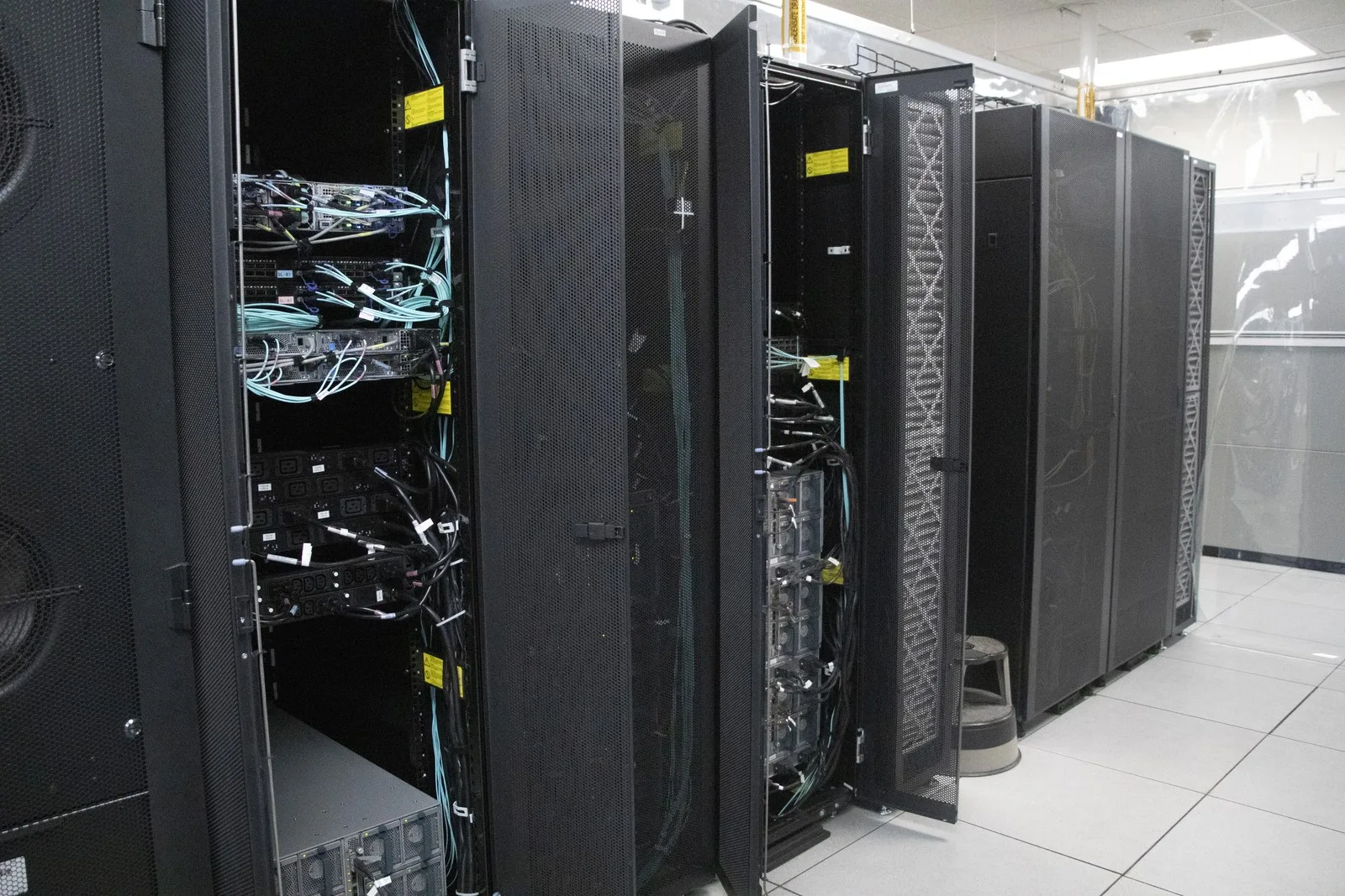 Open server racks reveal cable connections and computing equipment.